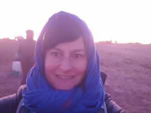 Foto von Sonja Warter mit einer Kopfbedeckung in der Wüste. 