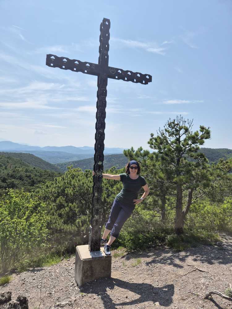 Sonja Warter hält sich an einem Gipfelkreuz fest und schwingt.