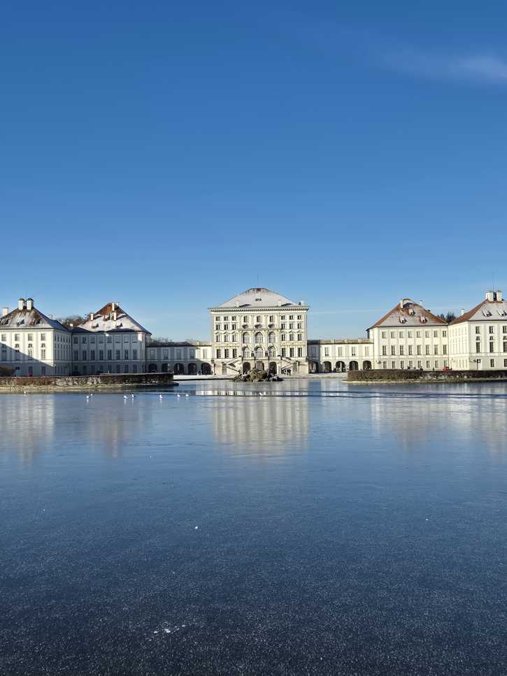 Schloss Nymphenburg in München mit Teich im Vordergrund.