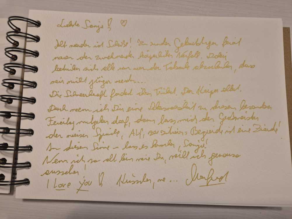 Handgeschriebener Text mit goldener Farbe auf weißem Papier.