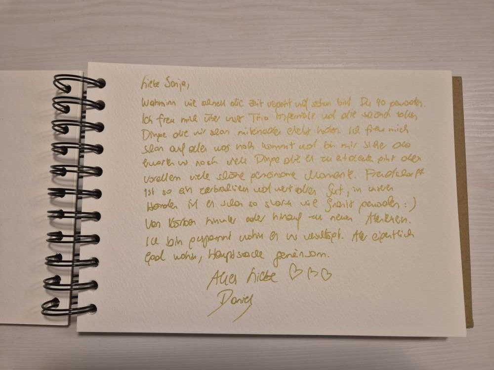 Handgeschriebener Text mit goldener Farbe auf weißem Papier.