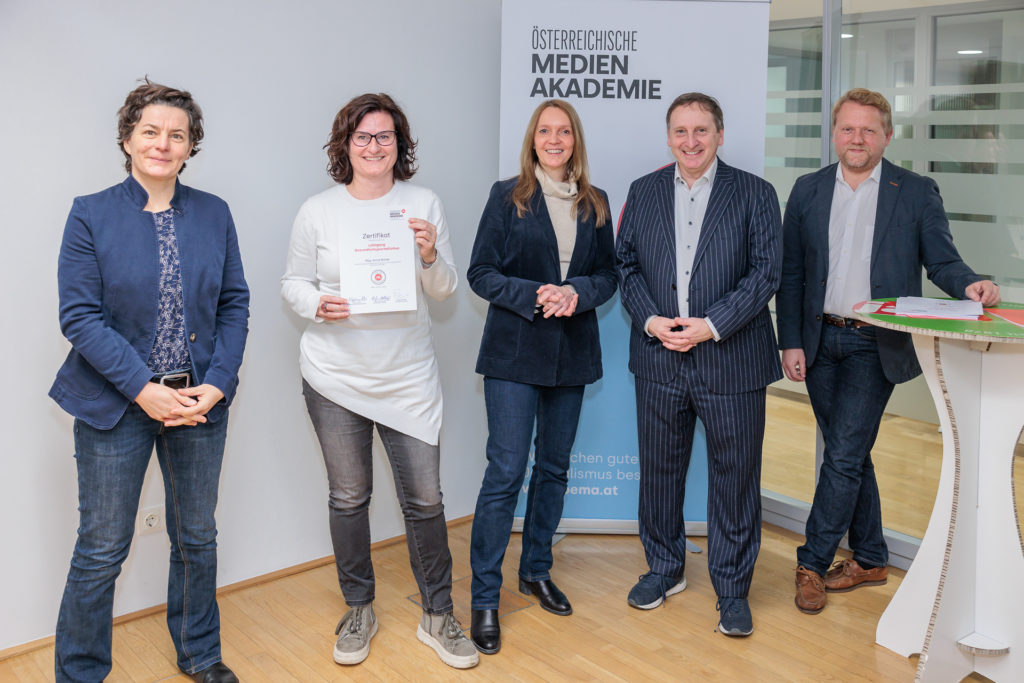 Sonja Warter, Martin Rümmele, Evelyn Holley-Spieß, Nikolaus Koller und eine weitere Frau vor einem Roll-up der Österreichischen Medienakademie. Sonja Warter hält Zertifikat in Händen.